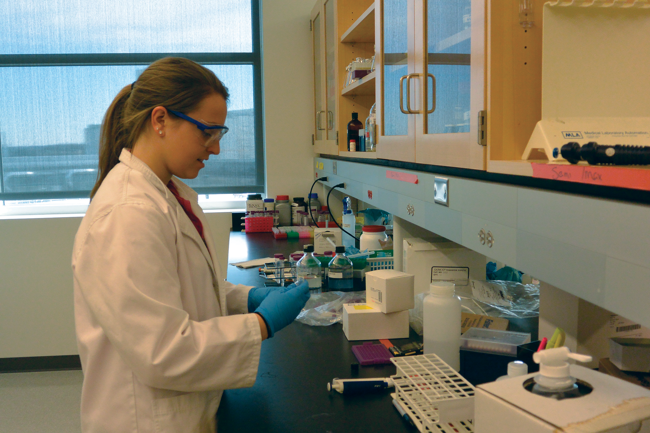 A scientist in a lab extracting materials for testing