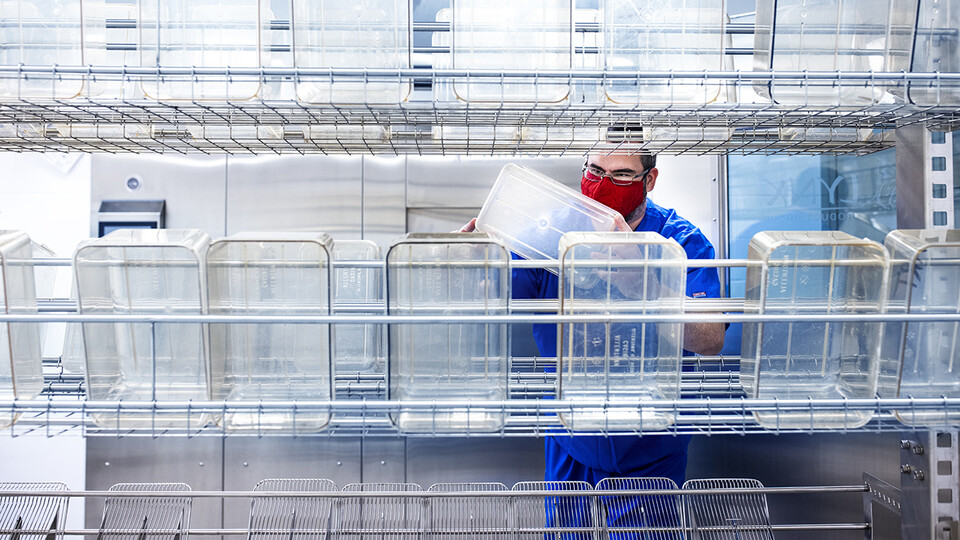 A scientist behind a large rack of containers