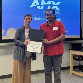 Department head giving an award to a student with a presentation screen behind them.