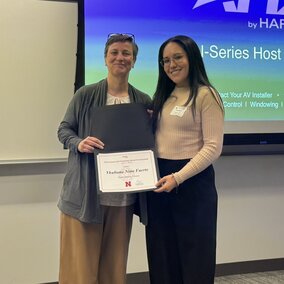 Department head giving an award to a student with a presentation screen behind them.